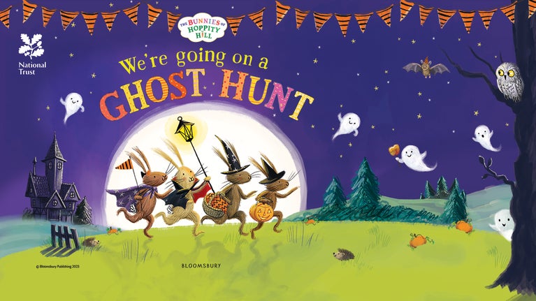 Children's book ilustration of four rabbits in Halloween costumes on hind legs running across a lawn at night, with ghosts and a spooky house in the background